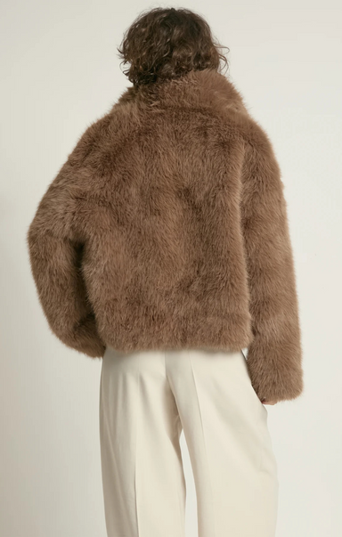 Person wearing a brown fluffy jacket on a plain background