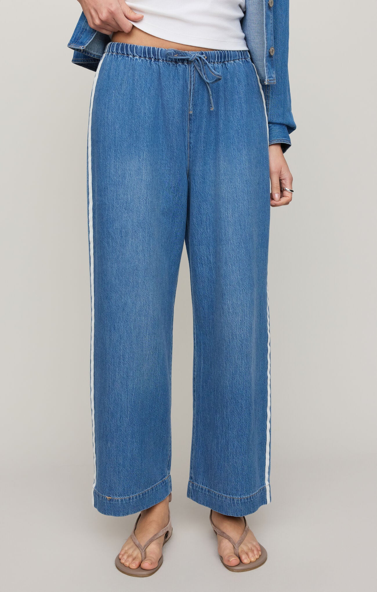 Blue jeans worn by a person on a plain background