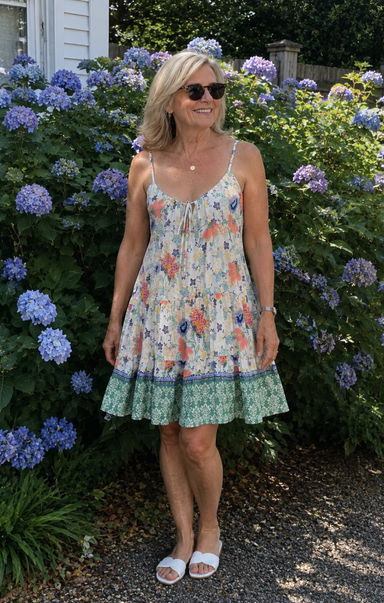 Woman in a floral dress standing in front of hydrangea bushes