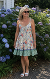 Woman in a floral dress standing in front of hydrangea bushes
