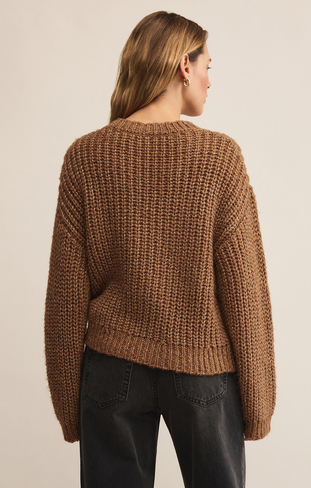 Person wearing a brown knitted sweater on a beige background
