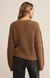 Person wearing a brown knitted sweater on a beige background