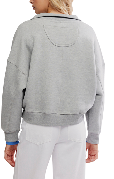A person shown from the back wearing a light gray cropped hoodie with a large back pocket, paired with white pants, against a plain white background.