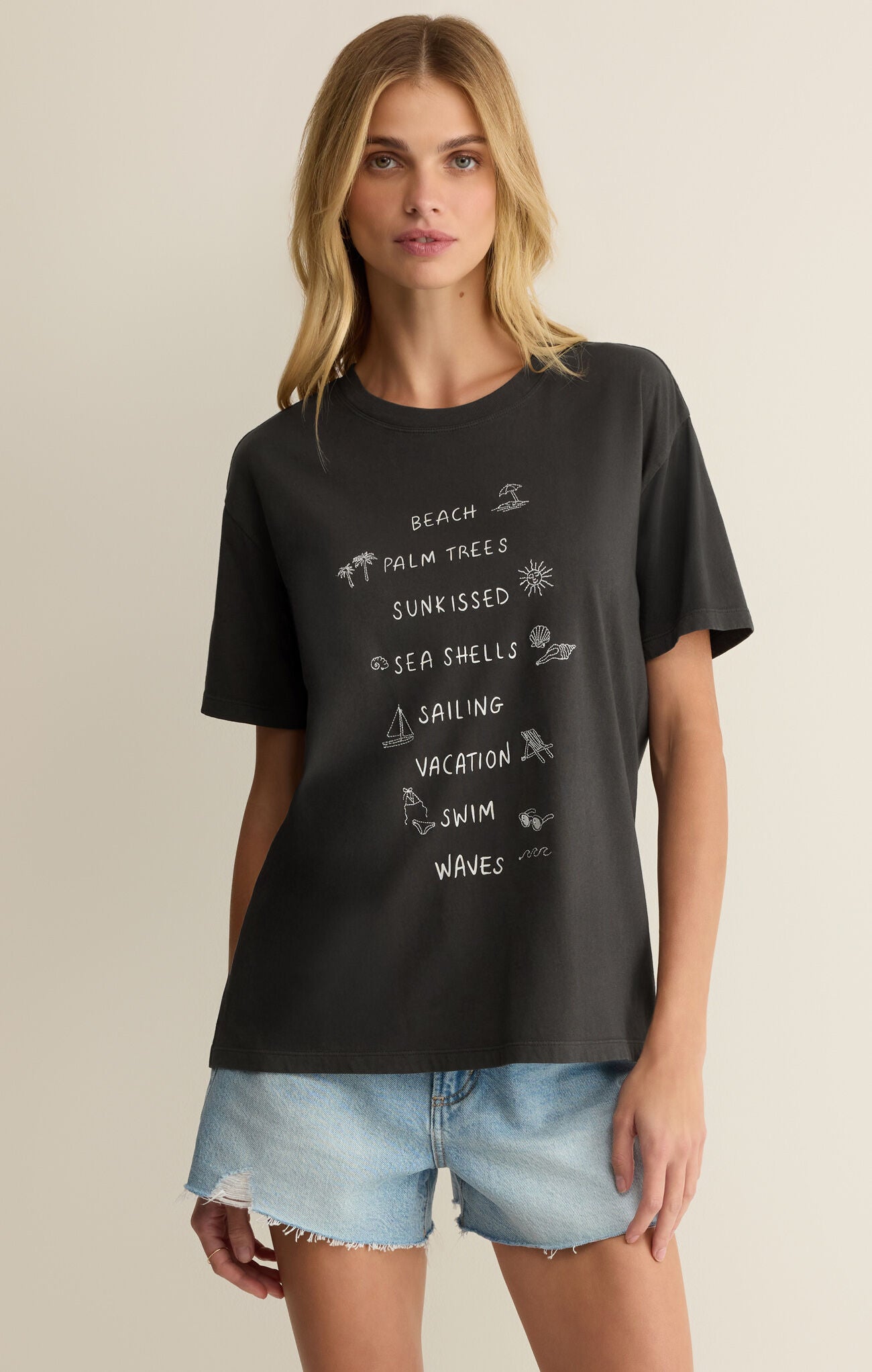 Woman wearing a black t-shirt with beach-themed graphics and text.