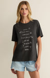 Woman wearing a black t-shirt with beach-themed graphics and text.