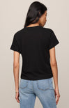 Person wearing a black t-shirt and blue jeans on a beige background