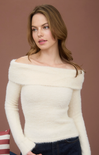 Woman wearing a white off-shoulder sweater against a brown background