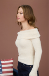 Woman wearing a white off-shoulder sweater against a brown background