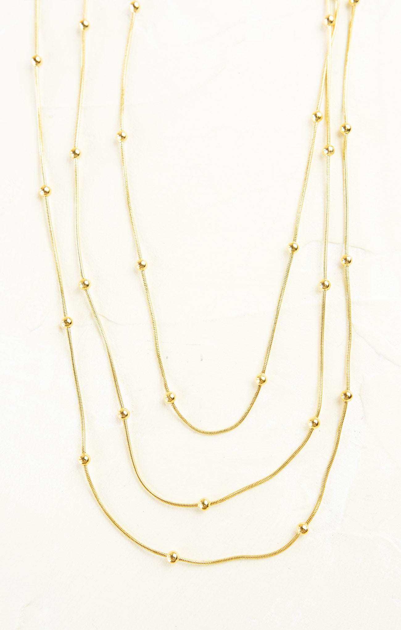 Three gold necklaces of different lengths on a white background