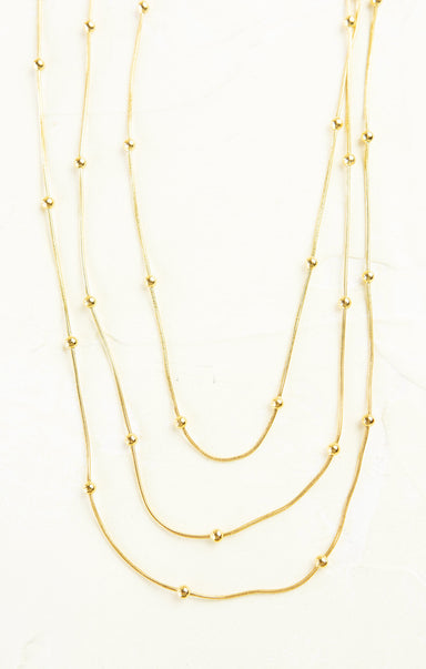 Three gold necklaces of different lengths on a white background