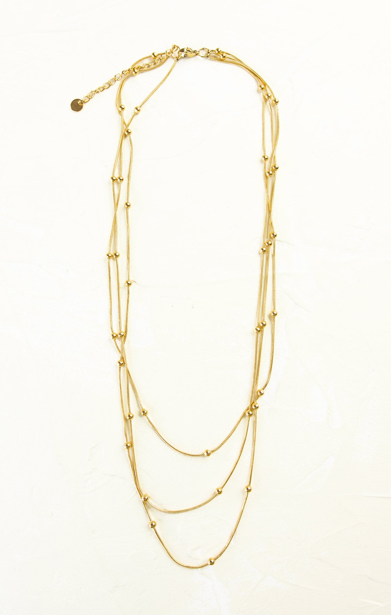 Gold necklace with multiple layers on a white background