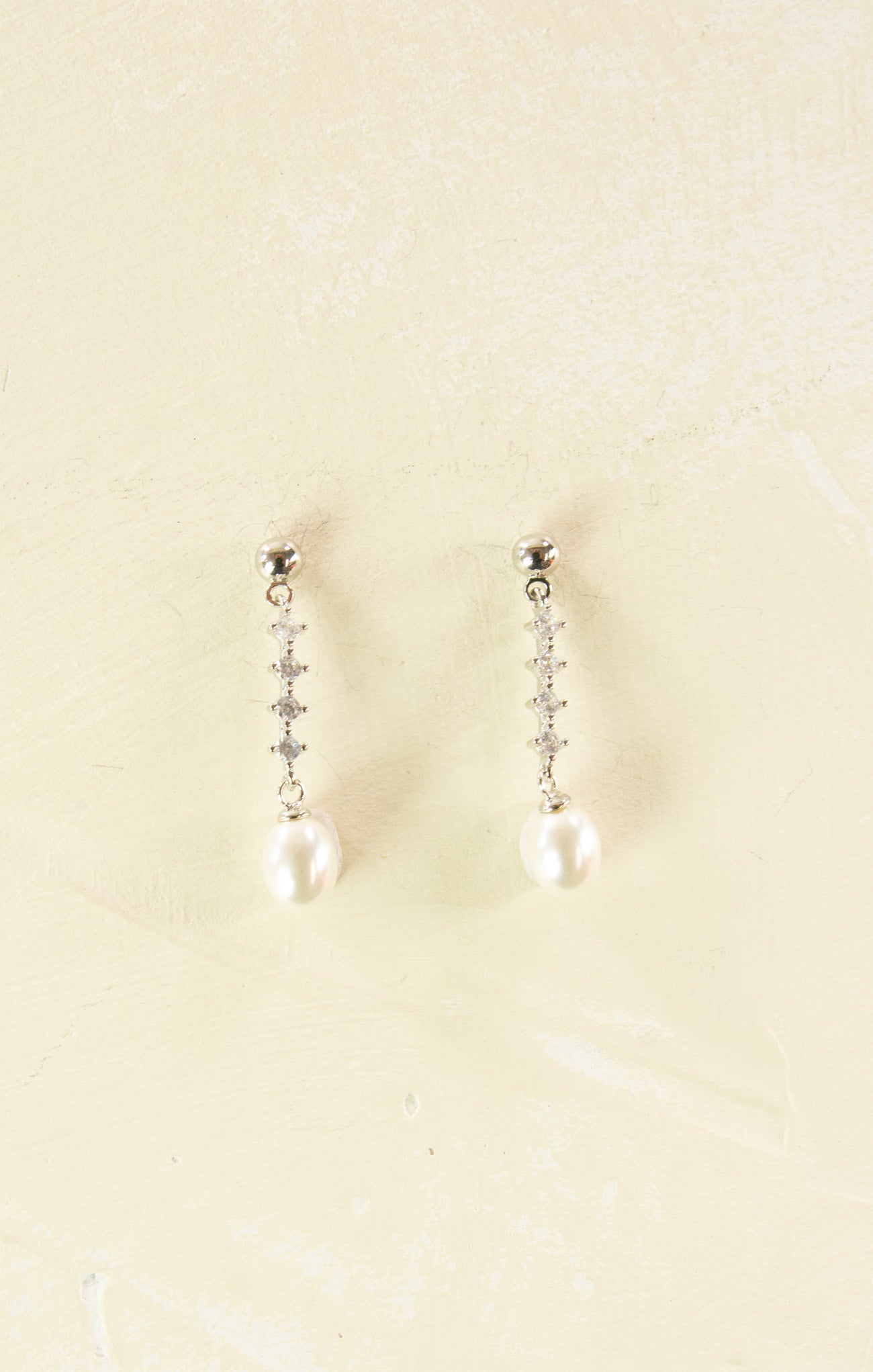 Pair of pearl earrings on a beige background