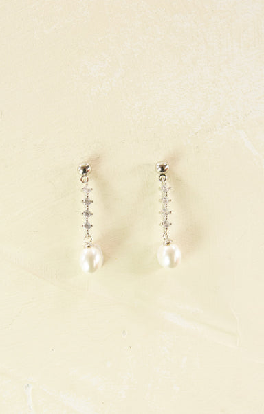 Pair of pearl earrings on a beige background