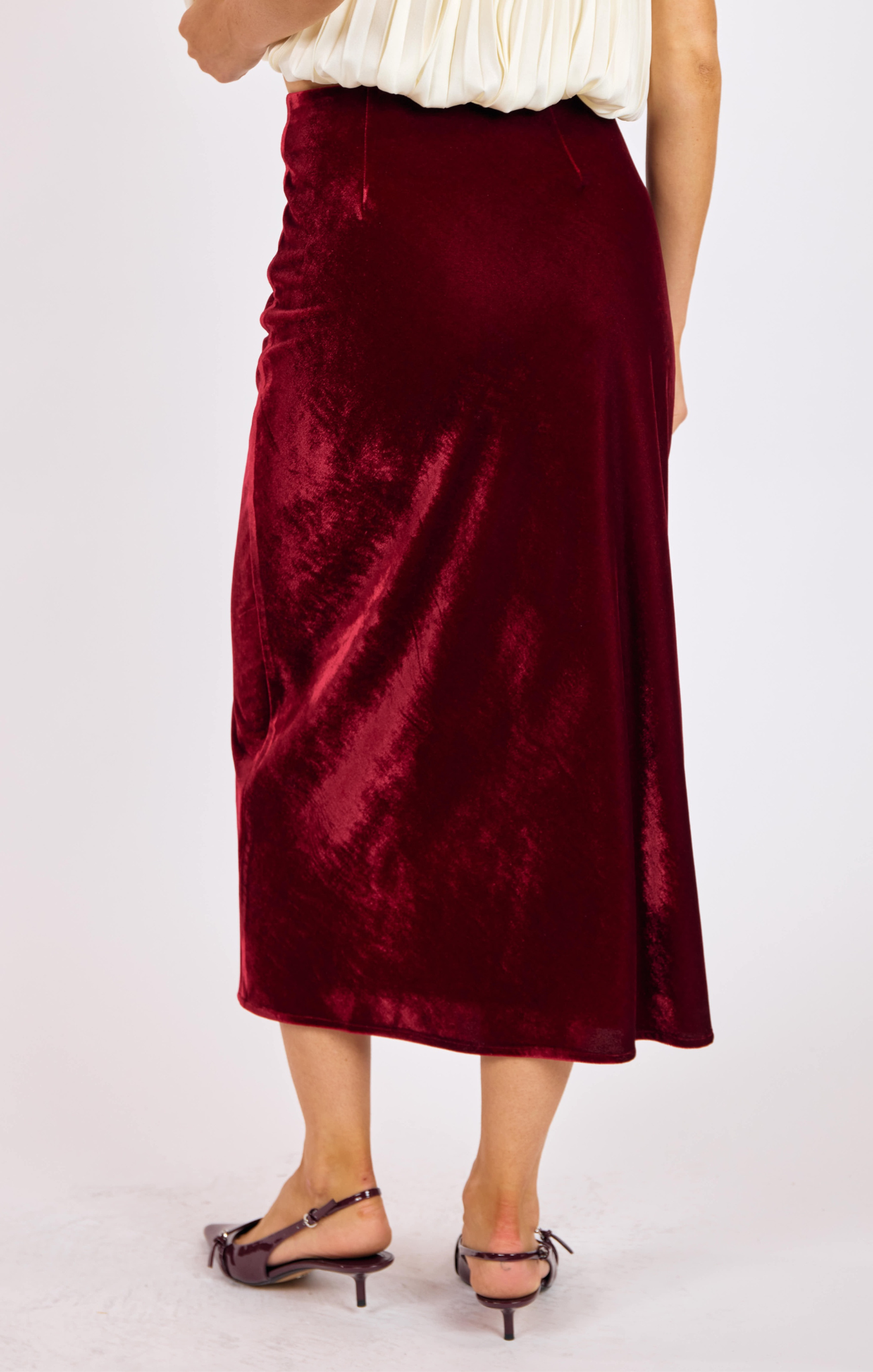 Burgundy velvet skirt worn by a person on a white background