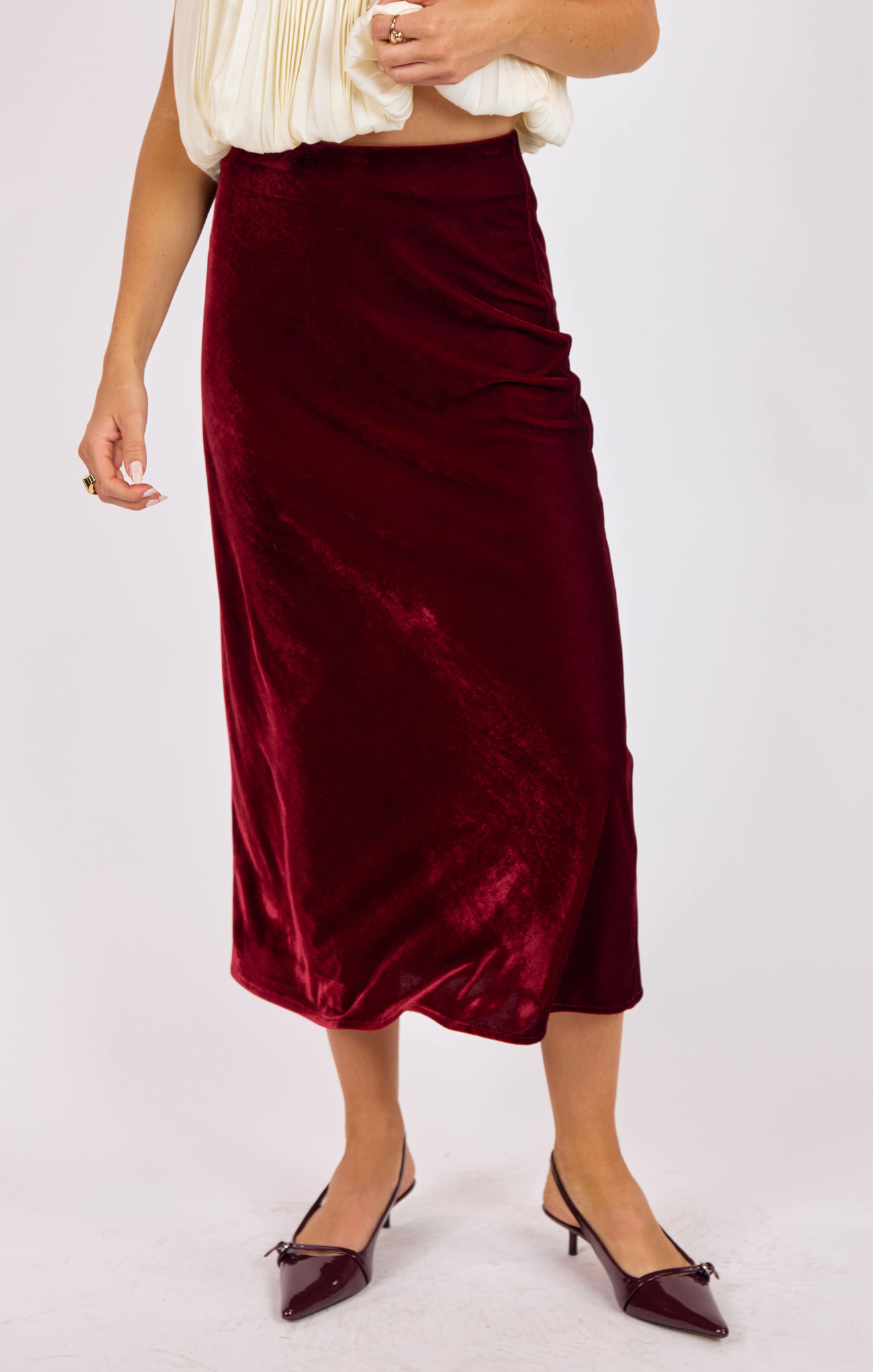 Burgundy velvet skirt worn by a person on a white background