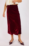 Burgundy velvet skirt worn by a person on a white background