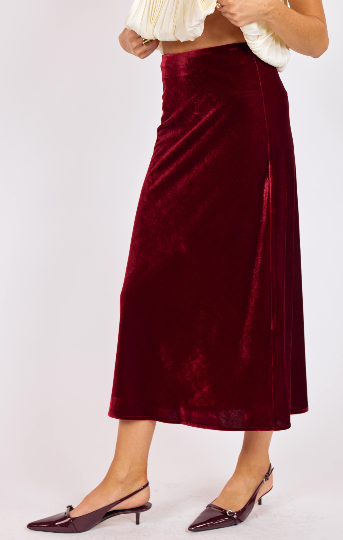 Burgundy velvet skirt worn by a person on a white background