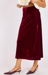 Burgundy velvet skirt worn by a person on a white background