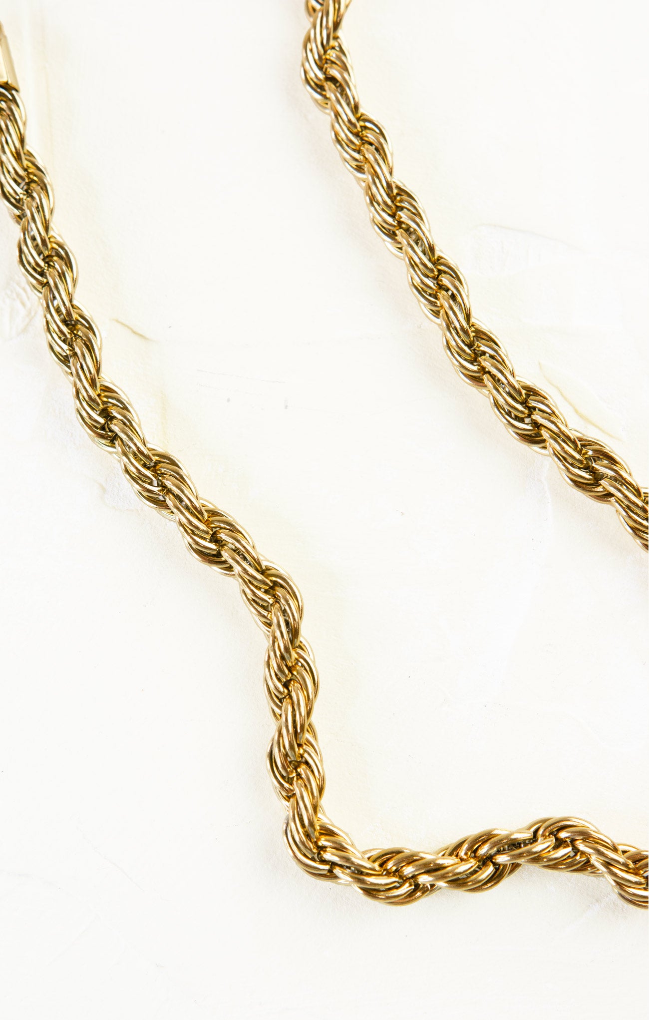 Gold rope chain necklace on a white background