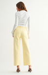 Woman wearing a white long-sleeve top and light yellow pants on a white background