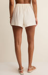 Person wearing white shorts on a beige background