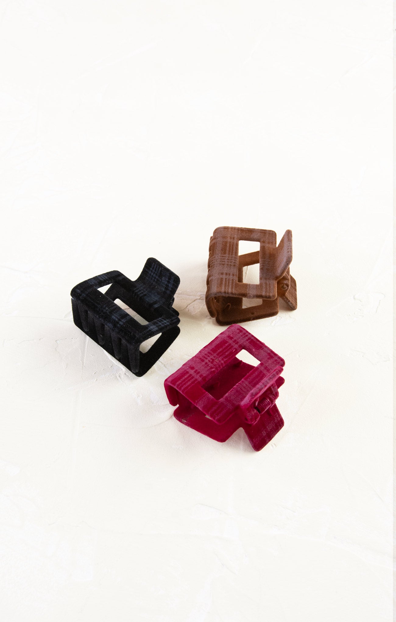 Three plastic clips in black, brown, and red on a white background