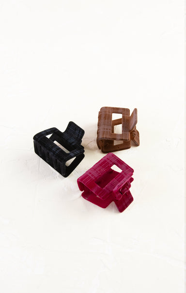 Three plastic clips in black, brown, and red on a white background
