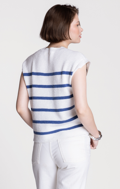 Woman wearing a white sleeveless top with blue stripes on a plain background