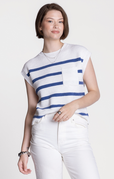 Woman wearing a white and blue striped shirt with white pants on a plain background