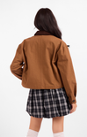 Person wearing a brown jacket and plaid skirt on a white background