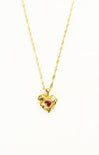 Gold heart-shaped necklace with a red gemstone on a white background