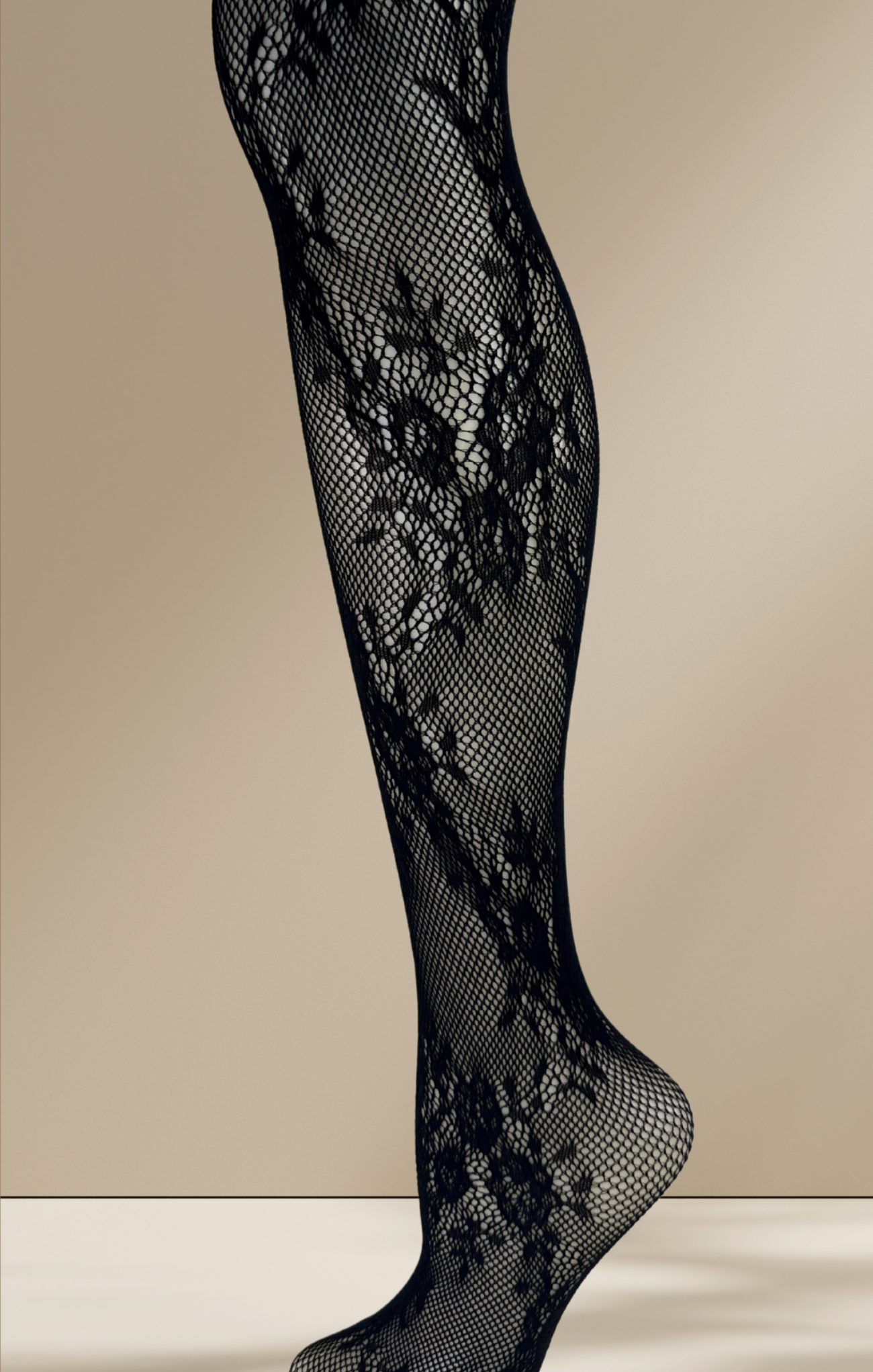 Black fishnet stockings with floral lace design on a beige background