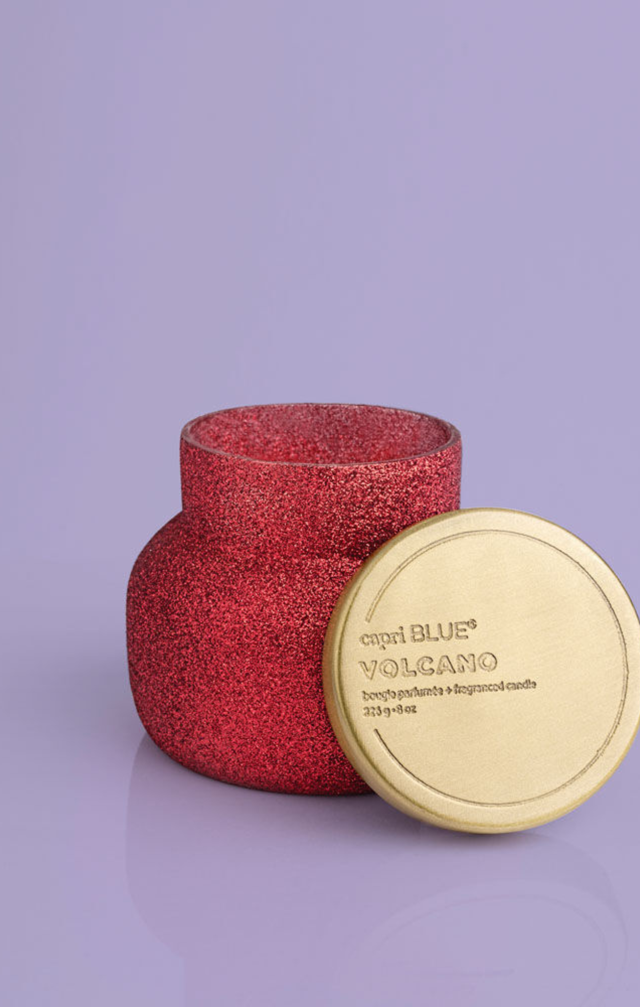 Red textured candle with a gold lid on a purple background