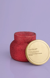 Red textured candle with a gold lid on a purple background