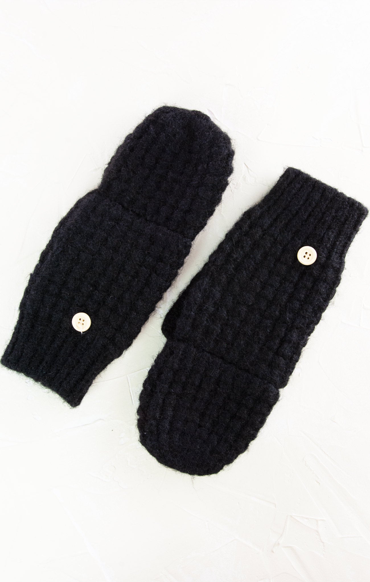 Pair of black knitted mittens with button closures on a white background