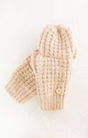Pair of beige knitted mittens with a button on a white background