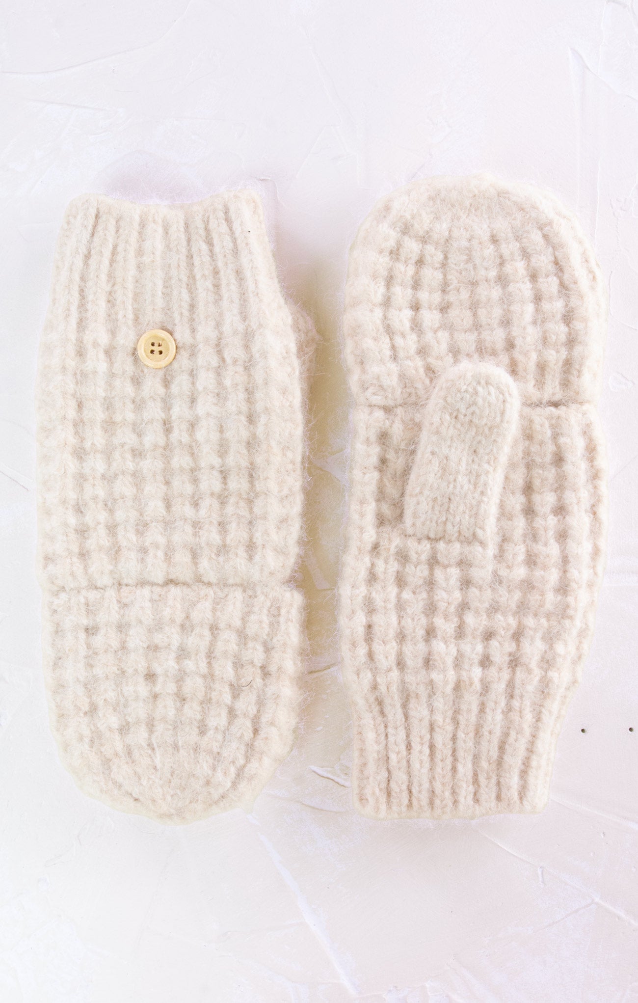 Pair of cream-colored knitted mittens on a white background