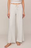 Person wearing light-colored wide-leg pants on a plain background