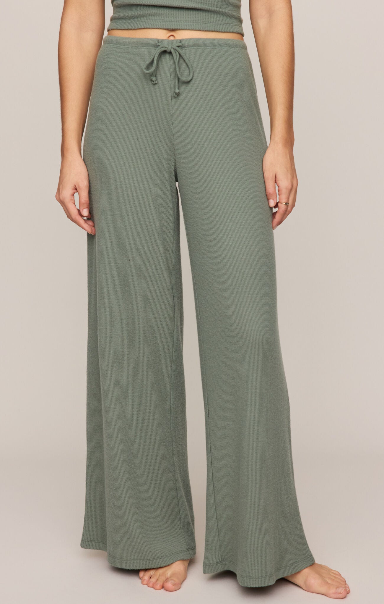 Person wearing green lounge pants on a plain background