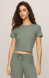 Woman wearing a green crop top and pants on a plain background