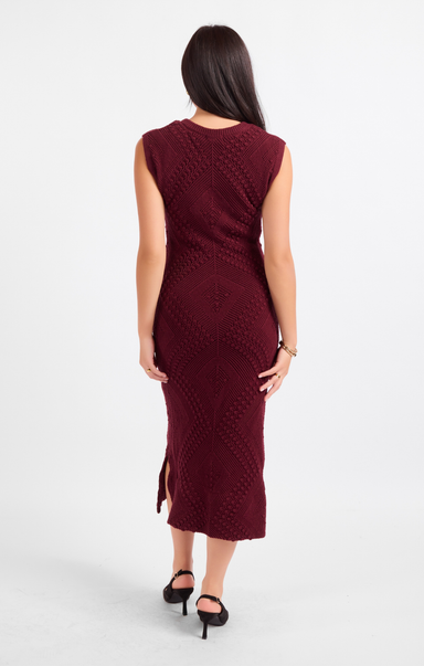Woman wearing a burgundy dress with a subtle pattern on a white background