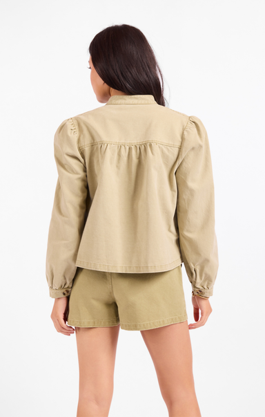 Person wearing a beige jacket and shorts set on a white background