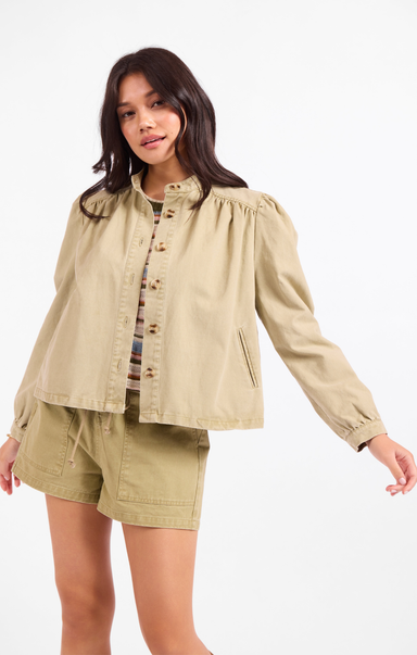 Woman wearing a beige jacket and shorts on a white background
