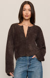 Woman wearing a brown fuzzy sweater and blue jeans against a plain background