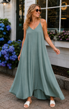 Woman wearing a long green dress standing in front of a building with flowers.
