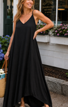 Woman wearing a black dress standing outdoors with flowers and a building in the background