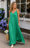 Woman in a green dress standing outdoors with flowers and a building in the background