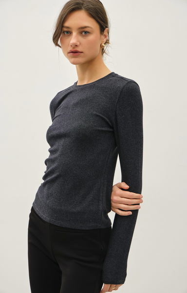 Woman wearing a dark gray long-sleeve top against a white background