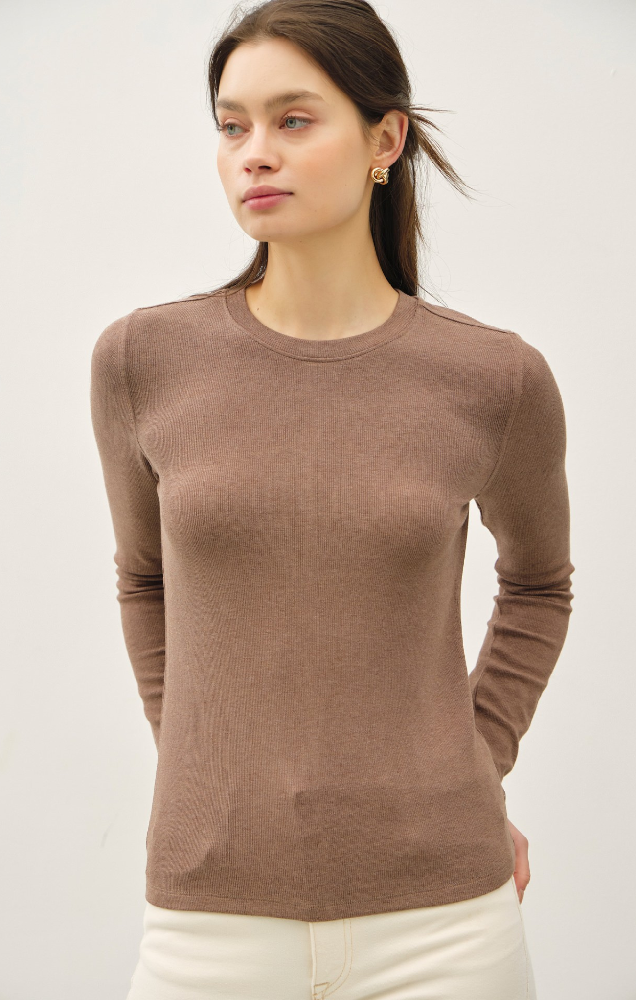Woman wearing a brown long-sleeve top against a white background