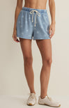 Light blue denim shorts with white drawstring worn by a person on a beige background